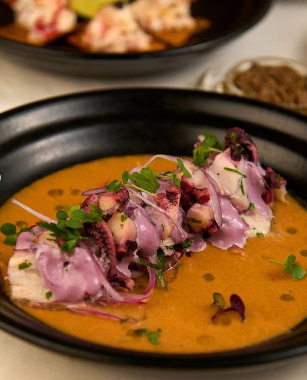 Pulpo al olivo sobre salsa de ají amarillo en plato negro